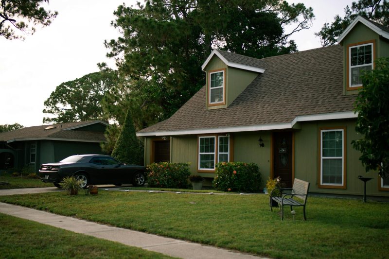 Beautiful suburban home with a manicured green lawn and a parked car in a residential setting.