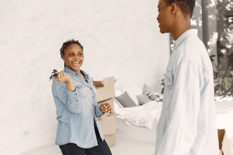 Smiling couple indoors happily holding a set of house keys in their new home.