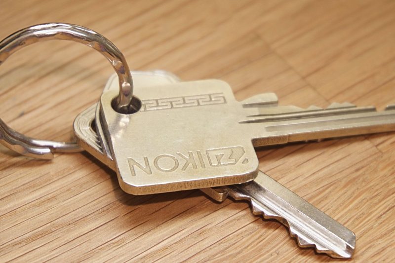 Set of metal house keys resting on a textured wooden surface.