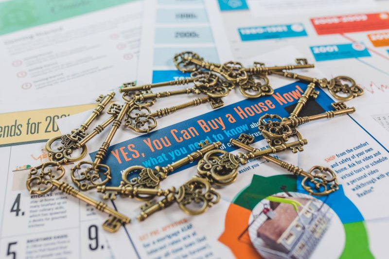 Vintage keys scattered on a real estate brochure featuring house buying information.